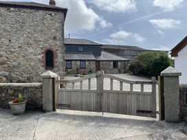 A stone building with a wooden gate and gravel driveway at Riviere House Hayle