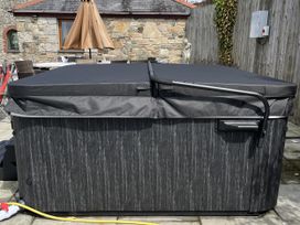A hot tub covered with a black lid at Riviere House in Hayle