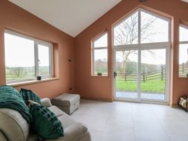 A snug with a sofa and windows overlooking a garden at Y Stabal near Llanilar