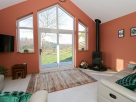 A living room with a stove and large windows at Y Stabal near Llanilar