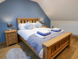 A bedroom with a wooden bed and bedside table at Y Stabal near Llanilar