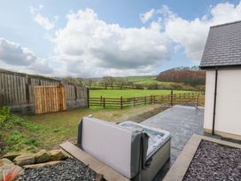 A garden with a hot tub and a wooden gate at Y Beudy near Llanilar