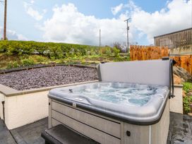 A hot tub in a garden area with gravel and landscaping at Y Beudy near Llanilar