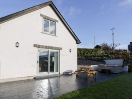 An outdoor view of a house with a patio, table, and hot tub at Beudy near Llanilar