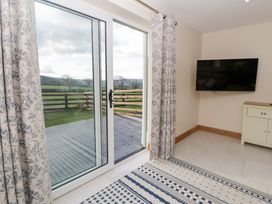 A living room with a sliding door and television at Beudy near Llanilar