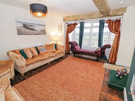 A sitting room with beige sofas orange cushions a purple chaise longue orange rug and window with curtains at Riverside Manor in Evesham