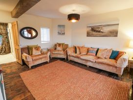 A living room with sofas and armchairs around a rug and wall art at Riverside Manor in Evesham