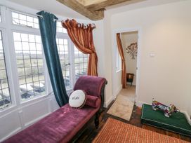 A room with a purple chaise lounge and windows with curtains overlooking a river at Riverside Manor in Evesham