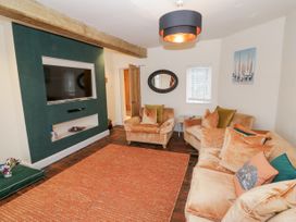 A living room with sofas a wall-mounted TV and an orange rug at Riverside Manor in Evesham