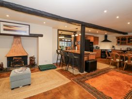 An open living space with a fireplace ottoman kitchen island with stools dining table and wooden beams at Riverside Manor in Evesham