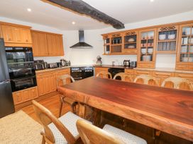 A kitchen with wooden cabinets a wooden dining table with chairs black appliances and a black ceiling beam at Riverside Manor in Evesham