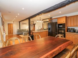An open-plan kitchen and living area with a wooden dining table chairs a sofa kitchen cabinets and appliances at Riverside Manor in Evesham