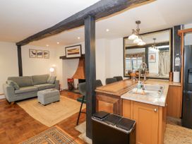 An open living room and kitchen area with a grey sofa and ottoman near a fireplace and a kitchen counter with a sink and mirror at Riverside Manor in Evesham