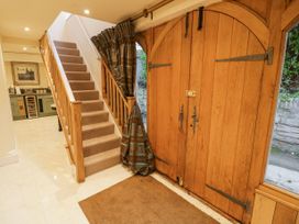 An entryway with wooden double doors a staircase with carpet and a kitchen area visible at Riverside Manor in Evesham