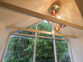 A large triangular window with beams and hanging round light fixtures showing trees outside at Riverside Manor in Evesham