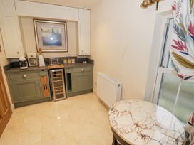 A kitchen area with green cabinets a wine cooler a marble table and patterned curtains at Riverside Manor in Evesham