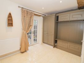 A room with beige tiled floor a grey built in cabinet beige curtains on glass door and a wooden boat shelf on the wall at Riverside Manor in Evesham