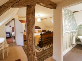 A bedroom with wooden bed frame and patterned rug a small adjacent room with a bed and a bathroom with patterned wallpaper at Riverside Manor in Evesham