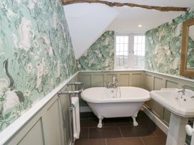 A bathroom with a clawfoot bathtub a pedestal sink and bird patterned wallpaper at Riverside Manor in Evesham