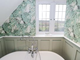 A bathtub with metal taps under a window with landscape view and floral bird wallpaper at Riverside Manor in Evesham