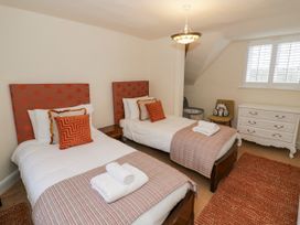 A bedroom with two single beds a white dresser and a chair with toys at Riverside Manor in Evesham