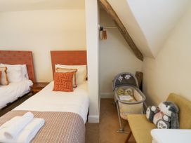 A bedroom with two single beds a baby bassinet and a chair with a stuffed animal at Riverside Manor in Evesham