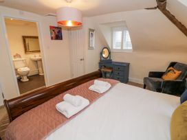 A bedroom with a bed and rolled towels a chair a dressing table and an en suite bathroom at Riverside Manor in Evesham