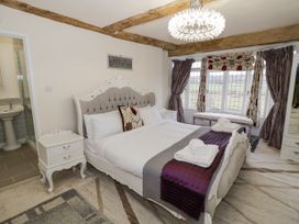 A bedroom with a bed folded towels bedside tables a bench in front of a window and bathroom visible at Riverside Manor in Evesham