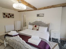A bedroom with a large ornate bed white furniture wooden ceiling beams and a floral painting at Riverside Manor in Evesham
