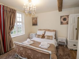 A bedroom with a bed sets with pillows and towels bedside tables curtains and a wardrobe at Riverside Manor in Evesham