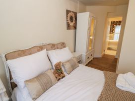 A bedroom with a bed pillows and a teddy bear next to a white wardrobe and a bathroom visible at Riverside Manor in Evesham