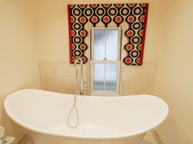 A bathroom with a white freestanding bathtub under a window with a patterned valance at Riverside Manor in Evesham