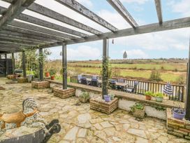 A covered stone patio with potted plants and outdoor dining furniture overlooking a grassy field at Riverside Manor in Evesham