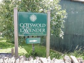 A sign for cotswold lavender growers and distillers next to a green corrugated building and trees at Riverside Manor in Evesham