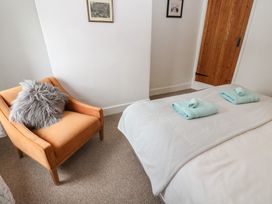 A bedroom with a chair and towels on the bed at 1 Eden Cottages in Corby Hill