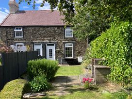 A garden with a stone house and patio at 2 Morfa View in Conwy