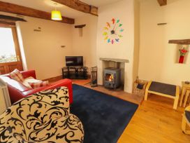 A living room with a wood stove and sofa at Beck Edge in Braithwaite