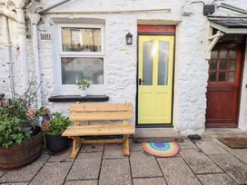 An outdoor area with a yellow door and wooden bench at Gosling Cottage in Kendal