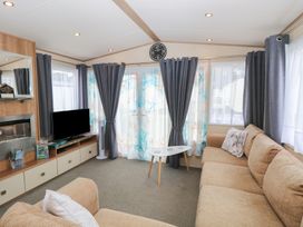 A living room with a television and sofa at Seashell Lodge, 50 Foxburrow Hang Belton, Norfolk