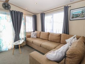 A living room with a couch and clock at Seashell Lodge, 50 Foxburrow Hang, Belton, Norfolk