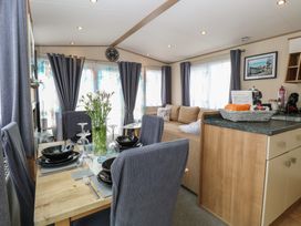 A living room with a dining table and sofa at Seashell Lodge, 50 Foxburrow Hang in Belton, Norfolk