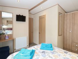 A bedroom with a bed and television at Seashell Lodge, 50 Foxburrow Hang Belton, Norfolk