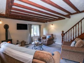 A living room with a stove and seating area at Bwthyn Derwin Fawr in Garndolbenmaen near Penygroes