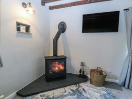 A snug with a fireplace and TV at Bwthyn Derwin Fawr in Garndolbenmaen near Penygroes