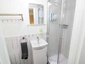 A bathroom with a shower, sink, and mirror at The Golden Cross Cottage Evesham