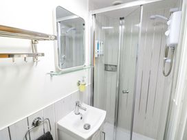A bathroom with a shower, sink, and mirror at The Golden Cross Cottage in Evesham