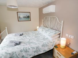 A bedroom with a bed, lamp, and painting at The Golden Cross Cottage in Evesham