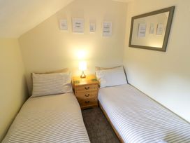 A bedroom with two beds and a bedside table at The Golden Cross Cottage in Evesham