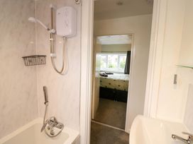 A bathroom with a shower and bath looking towards the bedroom at The Golden Cross Cottage in Evesham
