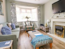 A living room with a sofa armchair ottoman fireplace and television at Branwen in Talacre